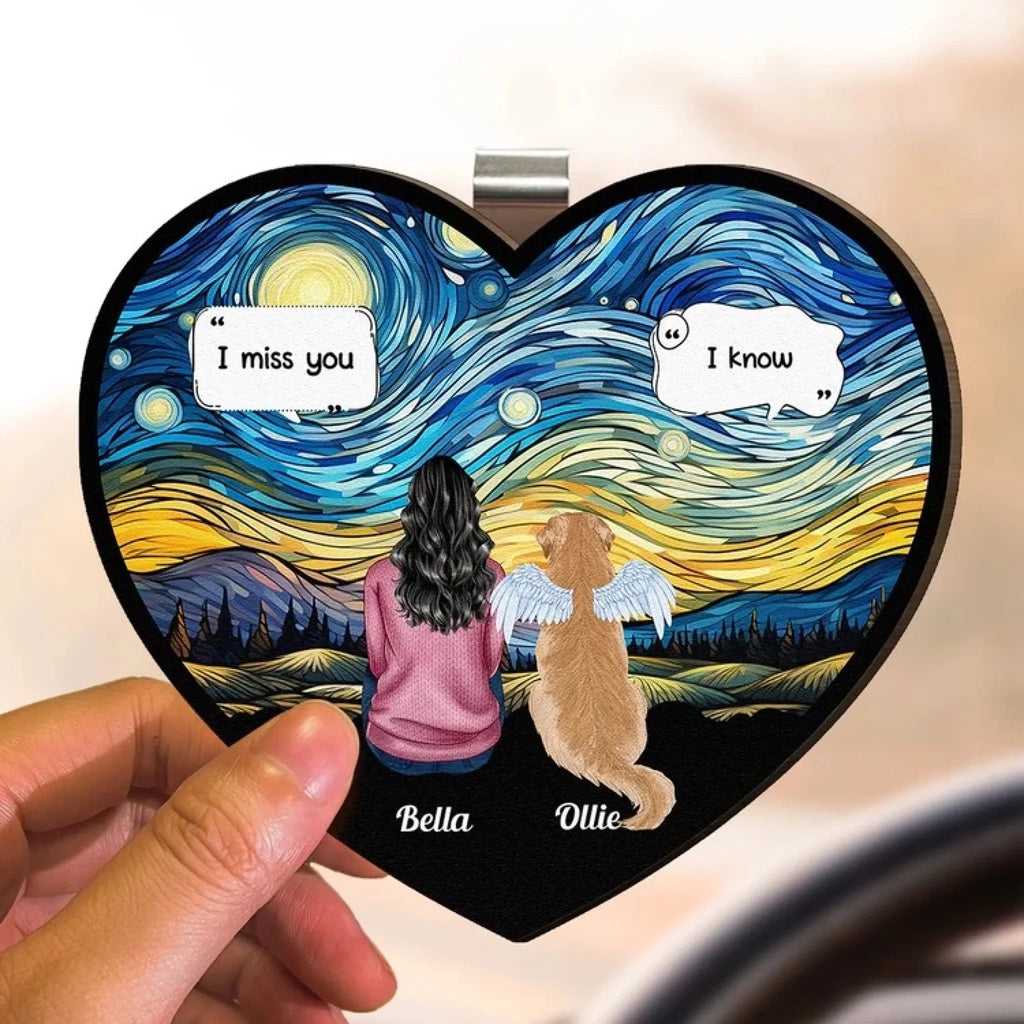 Hand holding a pet memorial visor clip with a woman, a dog with angel wings and the names Bella and Ollie