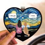 Hand holding a pet memorial visor clip with a woman, a dog with angel wings and the names Bella and Ollie
